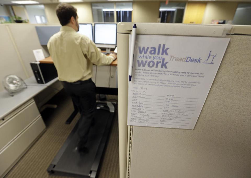 Josh Baldonado, an administrative assistant at Brown & Brown Insurance, works at a treadmill desk in the firms offices in Carmel, Ind., Wednesday, Aug. 28, 2013. Workers sign up for 30 slots not he treadmills and have their phone and computer transferred to the workstations. Being glued to your desk is no longer an excuse for not having time to exercise as a growing number of Americans are standing, walking and even cycling their way through the work day at treadmill desks, standup desks or other moving work stations. (AP Photo/Michael Conroy)