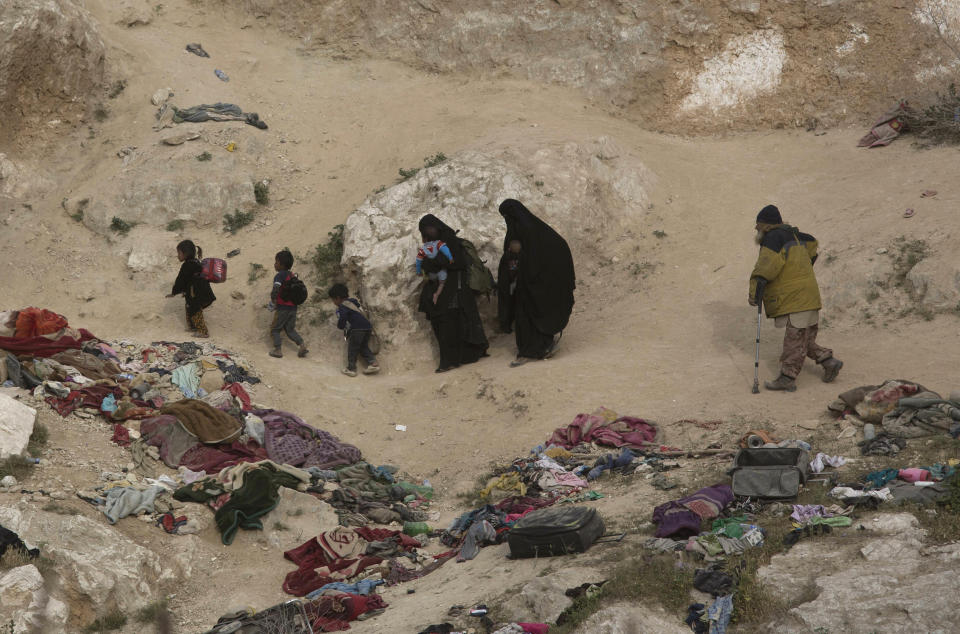 Women, children, and an injured man who left the besieged Islamic State-held village of Baghouz, Syria, scramble over a rocky hillside to be checked by U.S-backed Syrian Democratic Forces, Thursday, March 14, 2019. (AP Photo/Maya Alleruzzo)