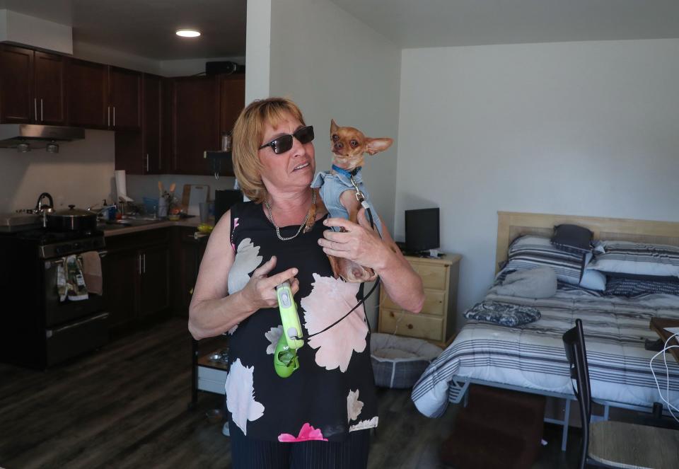 Susan Terry holds her dog Baby in her new home at the Cathedral Palms affordable housing community in Cathedral City, Calif., April 5, 2023.  Terry who had been unhoused prior to living here. 