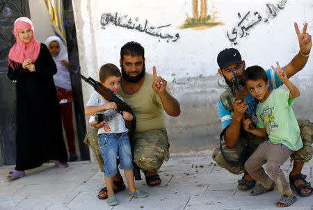 Turkish-backed Free Syrian Army (FSA) fighters pose with children in the border town of Jarablus, Syria, August 31, 2016. REUTERS/Umit Bektas