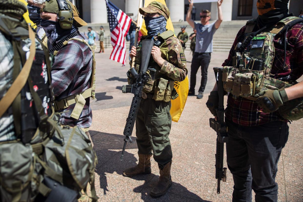 A local militia group is seen at a rally to protest a stay-at-home order in Columbus, Ohio, on April 20. The man in the center is wearing a "boogaloo" patch. (Photo: MEGAN JELINGER via Getty Images)