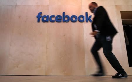 A man walks in front of the Facebook logo at the new Facebook Innovation Hub during a preview media tour in Berlin, Germany, February 24, 2016. REUTERS/Fabrizio Bensch/Files