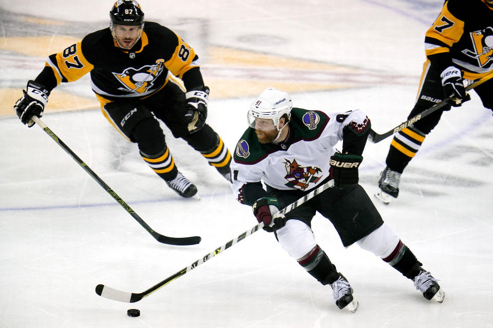 Arizona Coyotes' Phil Kessel (81) brings the puck up ice past Pittsburgh Penguins' Sidney Crosby (87) during the first period of an NHL hockey game in Pittsburgh, Tuesday, Jan. 25, 2022. (AP Photo/Gene J. Puskar)