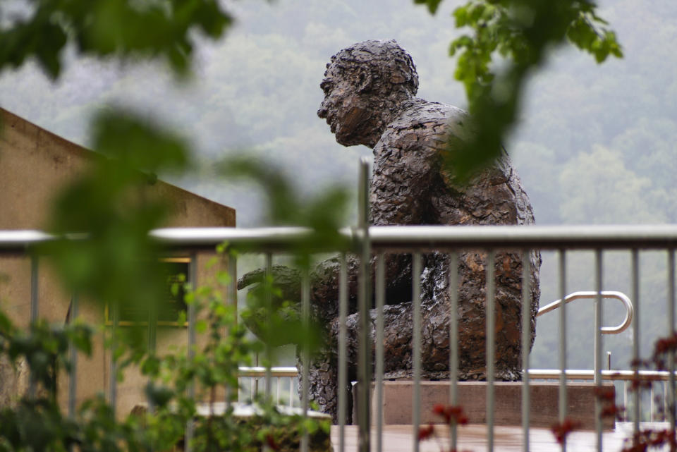 The statue of Public Broadcasting Service's Fred Rogers, the host of children's program "Mister Rogers' Neighborhood," is visible behind the fencing in the closed-off park area where the statue is located, during this year's "1-4-3 Day," Friday, May 22, the 143rd day of 2020, in Pittsburgh. In 2019, Pennsylvania Gov. Tom Wolf declared May 23, 2019, the first "1-4-3 Day," as a day of kindness in honor of Public Broadcasting Service's Fred Rogers, the host of children's program "Mister Rogers' Neighborhood." Rogers, a Pennsylvania native who died in 2003, used 143 as his special code for "I Love You," based on the number of letters in each word. (AP Photo/Keith Srakocic)