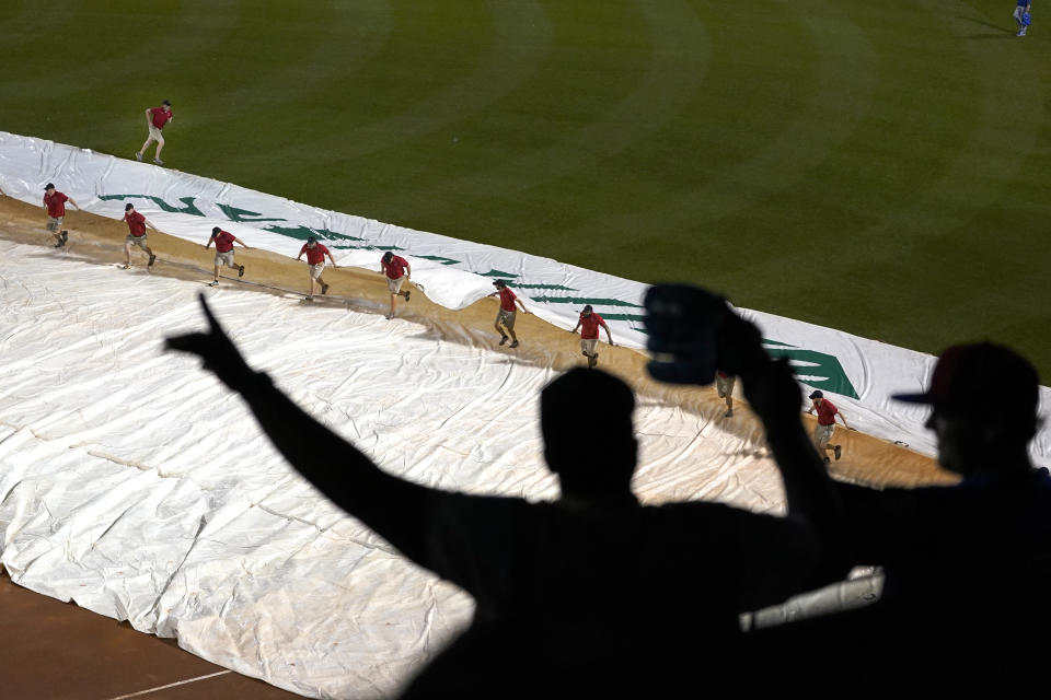 Fans in the upper deck dance to music as grounds crew members cover the Fenway Park infield with a tarp during a rain delay in the sixth inning of a baseball game between the Boston Red Sox and the Kansas City Royals, Wednesday, June 30, 2021, in Boston. (AP Photo/Elise Amendola)