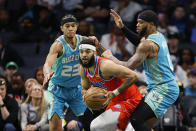 Oklahoma City Thunder forward Kenrich Williams, center, looks to pass out of a double team by Charlotte Hornets guard Tre Mann (23) and forward Miles Bridges, right, during the first half of an NBA basketball game in Charlotte, N.C., Sunday, April 7, 2024. (AP Photo/Nell Redmond)