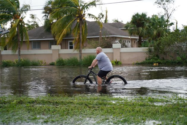A man tries to ride a bike in a road flooded by Hurricane Ian in Fort Myers. The bacteria grows faster in warmer months and can be amplified by sewage spills, according to health officials. (Photo: Anadolu Agency via Getty Images)