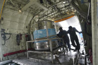 Tanks containing a solution of water and salt are loaded into a military plane at Subang Military airbase in Subang, Malaysia, Thursday, Sept. 19, 2019. Malaysian authorities plan to conduct a cloud-seeding operation to induce rain in an effort to ease the haze problem due to forest fires in neighboring Indonesia. (AP Photo/Vincent Thian)