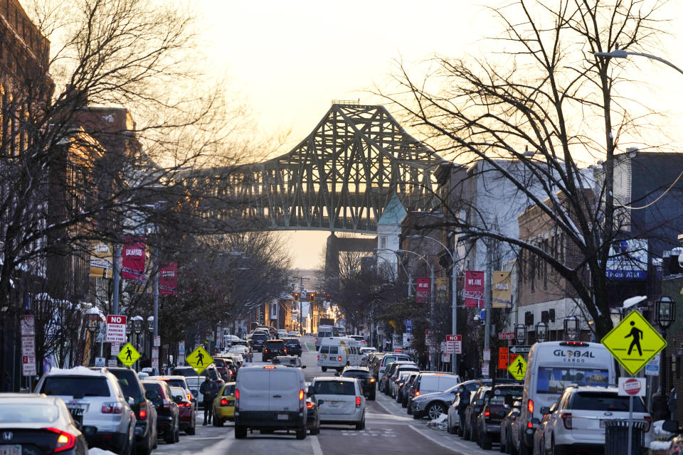 Tobin Bridge frames Broadway as traffic moves in downtown Chelsea, Mass., Feb. 10, 2021. Two predominantly Latino cities in neighboring states have had diverging fates in the global rollout of the coronavirus vaccine. Central Falls, R.I., and Chelsea, have been the states’ hardest-hit communities in the pandemic. Public health experts, civil rights groups and immigrant activists have complained for months that Massachusetts isn’t doing nearly enough to ensure that Black and Latino residents are inoculated. (AP Photo/Elise Amendola)