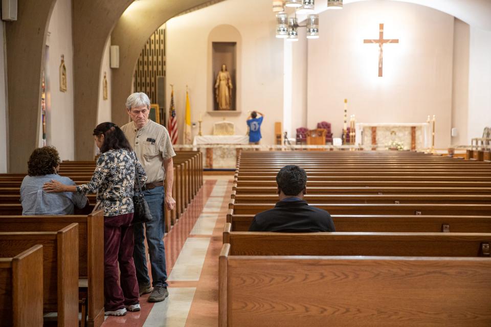 Rose Conner (center) comforts fellow Uvalde resident and member of the Sacred Heart Catholic Church congregation in Uvalde, Texas, before a 10 a.m. mass on May 25, 2022. Her husband, Bill Connor, a resident for 45 years, looks at empty pews.