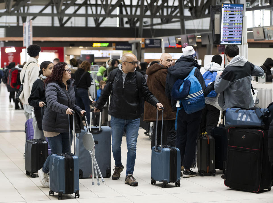 Travelers line up at the Ottawa International Airport, as airlines cancel or delay flights during a major storm in Ottawa, on Friday, Dec. 23, 2022. (Justin Tang /The Canadian Press via AP)