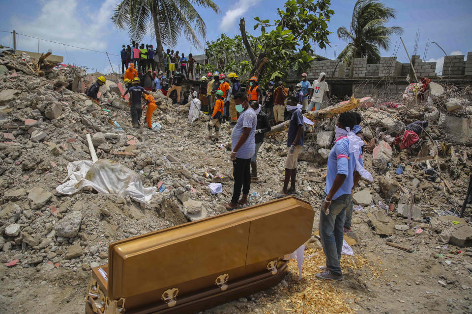 People stand next to the coffin that contains the remains of Francois Elmay whose body was recovered from the rubble of a home destroyed by Saturday's 7.2-magnitude earthquake, in Les Cayes, Haiti, Wednesday, Aug. 18, 2021. (AP Photo/Joseph Odelyn)