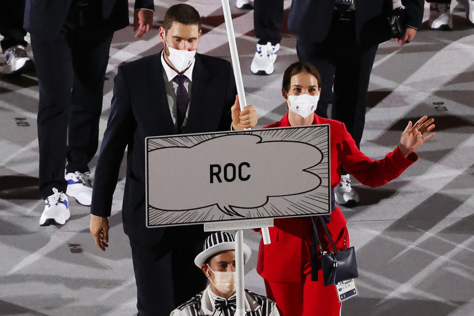 Fencer Sofya Velikaya (pictured right) and volleyball player Maxim Mikhailov (pictured left) of the ROC Team carry a ROC flag during the Parade of Nations at the opening ceremony of the Tokyo 2020 Summer Olympic Games.