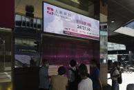 People walk past a bank's electronic board showing the Hong Kong share index at Hong Kong Stock Exchange Tuesday, Oct. 27, 2020. Shares skidded in Asia on Tuesday after surging coronavirus cases and waning hopes for U.S. economic stimulus gave Wall Street its worst day in a month. (AP Photo/Vincent Yu)