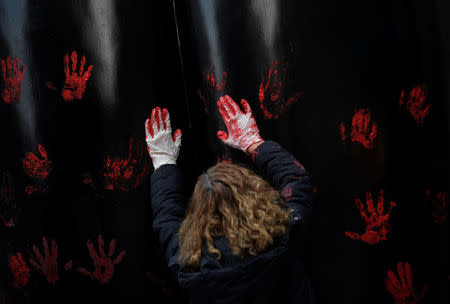 A woman puts her hands, smeared with red paint, on a sculpture during a protest after a Spanish court condemned five men accused of the group rape of an 18-year-old woman, in Oviedo, Spain April 26, 2018. REUTERS/Eloy Alonso