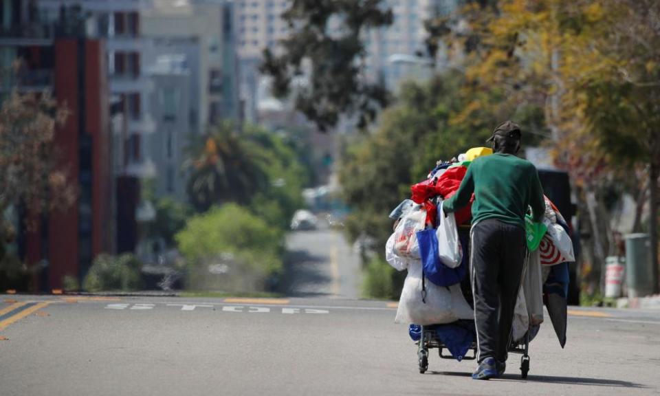 A homeless man pushes a cart full of his belongings along an empty street in San Diego. California has the largest homeless population in the US
