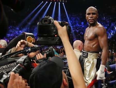 Floyd Mayweather, Jr. of the U.S. is surrounded by cameras after defeating Manny Pacquiao of the Philippines in their welterweight WBO, WBC and WBA (Super) title fight in Las Vegas, Nevada, May 2, 2015. REUTERS/Steve Marcus