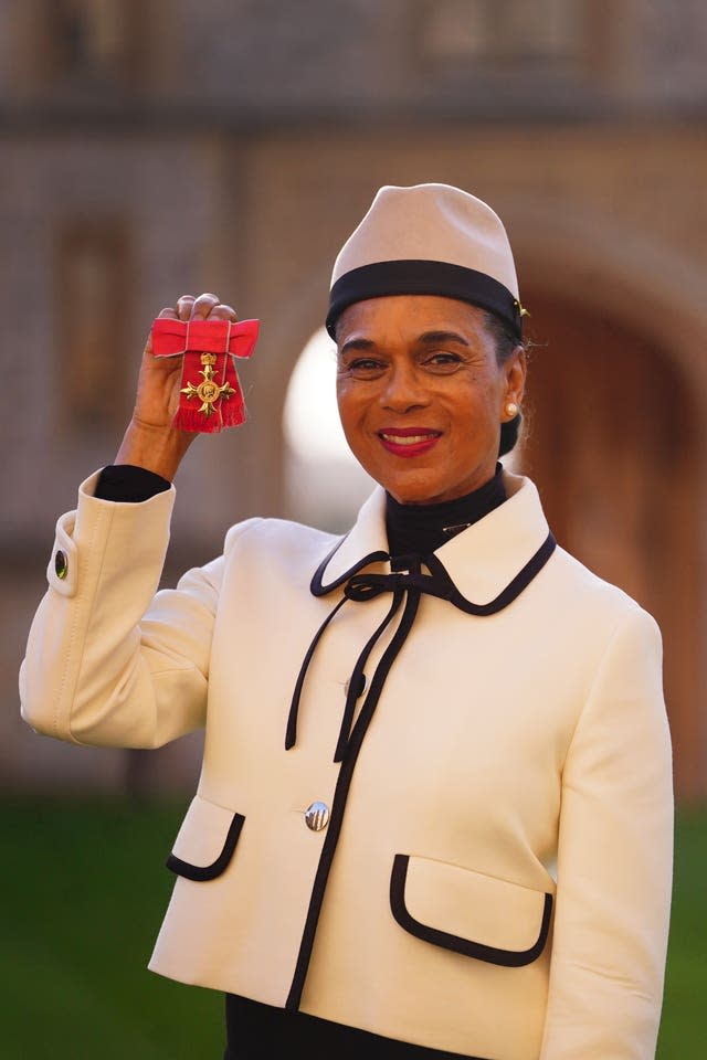 Pauline Black in a white suit jacket holding up a medal at investitures at Windsor Castle
