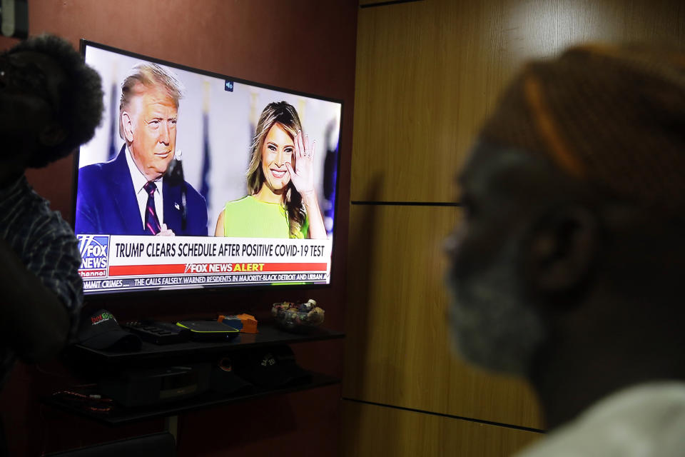 Accountant Abiodun Ayinde watches as the news announces U.S President Donald Trump and First Lady Melania Trump have tested positive for coronavirus, at his office in Lagos Friday, Oct. 2, 2020. Global markets dropped after President Trump said that he and the first lady had tested positive for the coronavirus. (AP Photo/Sunday Alamba)