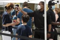 A customer has her temperature checked before entering the Apple Store, Saturday, July 11, 2020, in Boston. (AP Photo/Michael Dwyer)