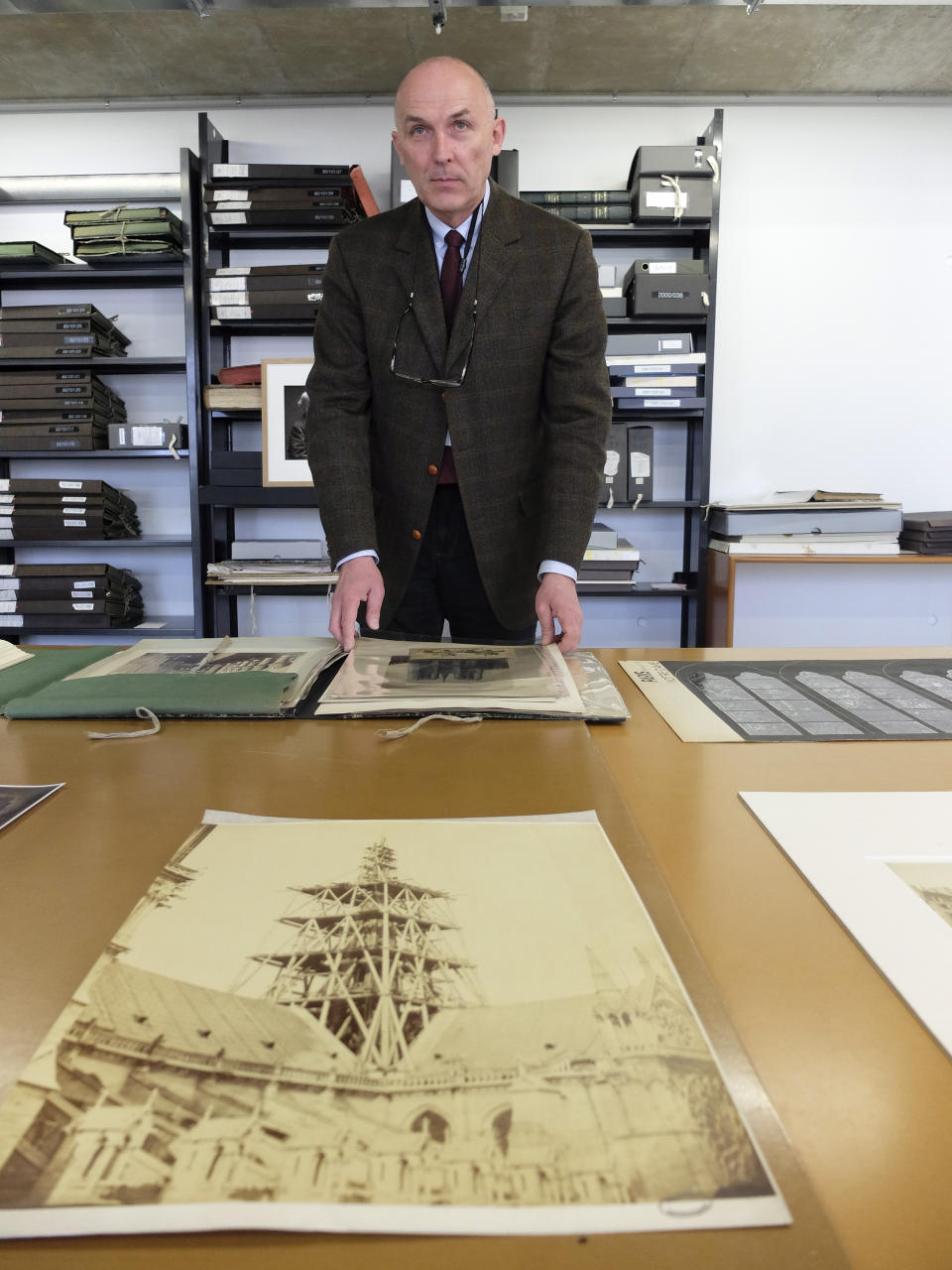 Jean-Charles Forgeret poses with archives documents related to Notre Dame cathedral in Charenton le Pont, outside Paris, Thursday, April 18, 2019. The reconstruction of Paris' Notre Dame Cathedral will rely on part on extensive plans drawn up in the 19th century for its last big renovation. Forgeret noted that the last restoration took 20 years, and cast doubt on the French president's 5-year deadline on fixing Notre Dame this time. (AP Photo/Nicolas Garriga)