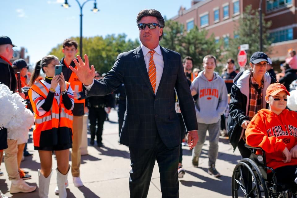 Oklahoma State coach Mike Gundy walks with child cancer survivors to Boone Pickens Stadium in Stillwater before the Cowboys' game against Kansas on Saturday.