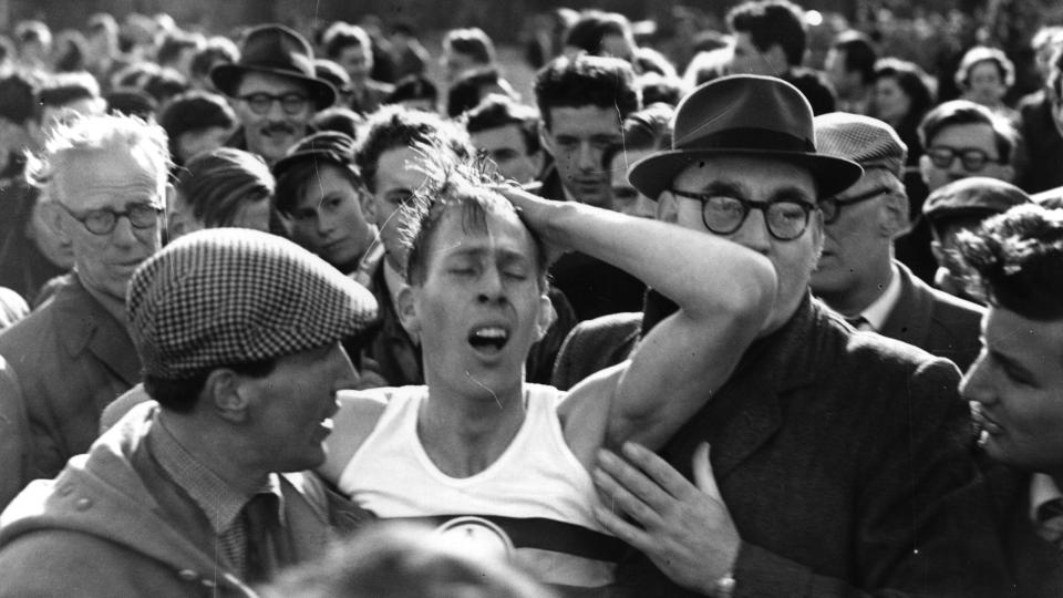 An exhausted Roger Bannister is surrounded by a crowd after running the first sub four-minute marathon