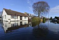 A four-wheel drive vehicle drives through flooded streets in Wraysbury in southern England, January 13, 2014. Britain's insurers are preparing to pay out hundreds of millions of pounds in claims following a run of winter storms that have flooded homes and disrupted travel, though the absence of major damage should limit the impact on their 2013 results. More than 1,700 homes and businesses have been affected by the floods in England since late December, which also killed seven people, according to news reports. REUTERS/Toby Melville (BRITAIN - Tags: ENVIRONMENT DISASTER)