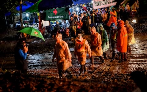 A group of policemen enters Tham Luang Nang Non cave where a a soccer team has gone missing - Credit: Getty