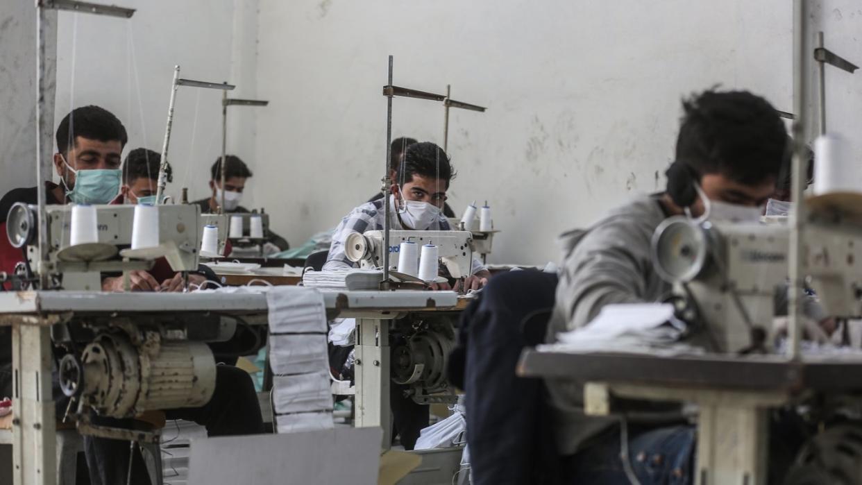 Arbeiter in der umkämpften Region Idlib mit Gesichtsmasken. In einem kleinen Labor stellen sie notdürftig Schutzmasken her.