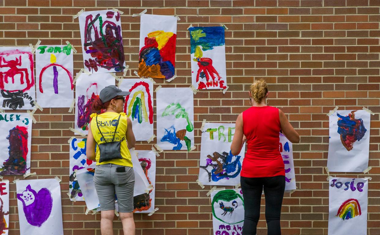 Volunteers are once again needed in various roles for Art Beat in downtown South Bend on Aug. 20, 2022. Here, helpers from the South Bend Museum of Art hang paintings created by children on the side of the Century Center during the 2019 Art Beat.