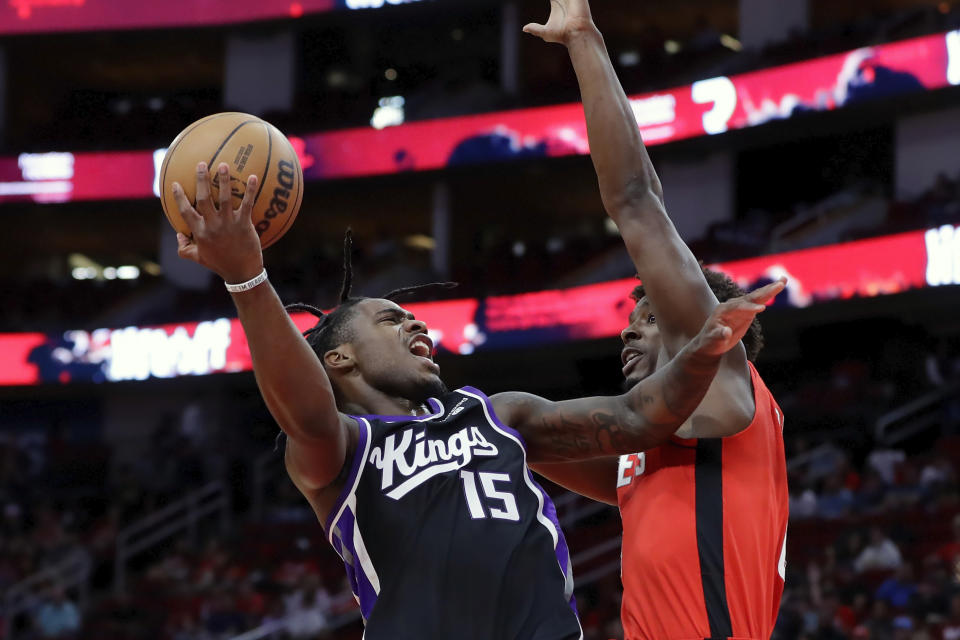 Sacramento Kings guard Davion Mitchell (15) lays up a shot against Houston Rockets forward Jae'Sean Tate during the first half of an NBA basketball game Monday, Nov. 6, 2023, in Houston. (AP Photo/Michael Wyke)