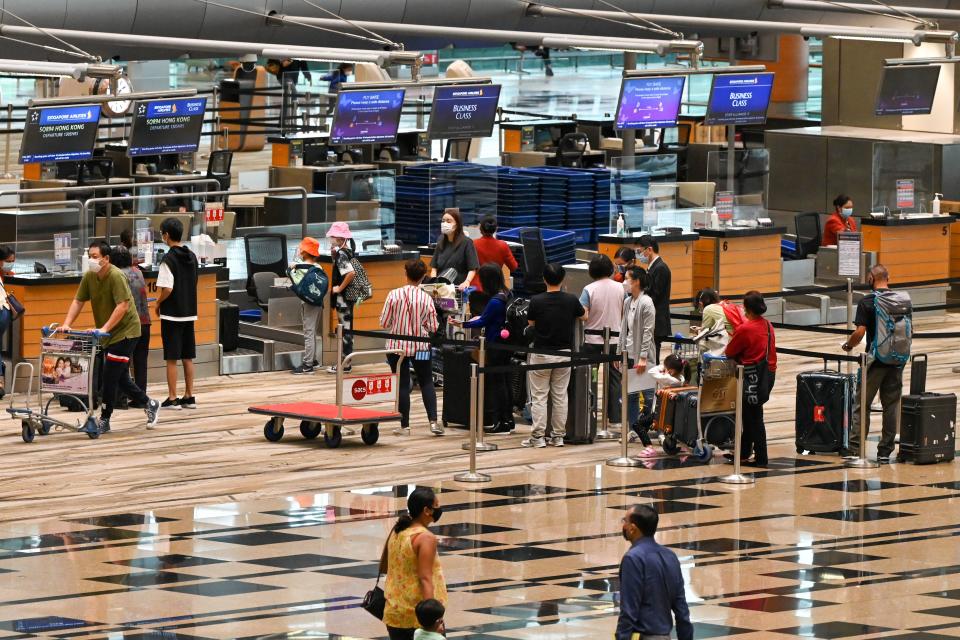 Travellers check in for the flight at the Singapore Airlines counter in the departure hall at Changi International Airport in Singapore on December 2, 2021. (Photo by Roslan RAHMAN / AFP) (Photo by ROSLAN RAHMAN/AFP via Getty Images)