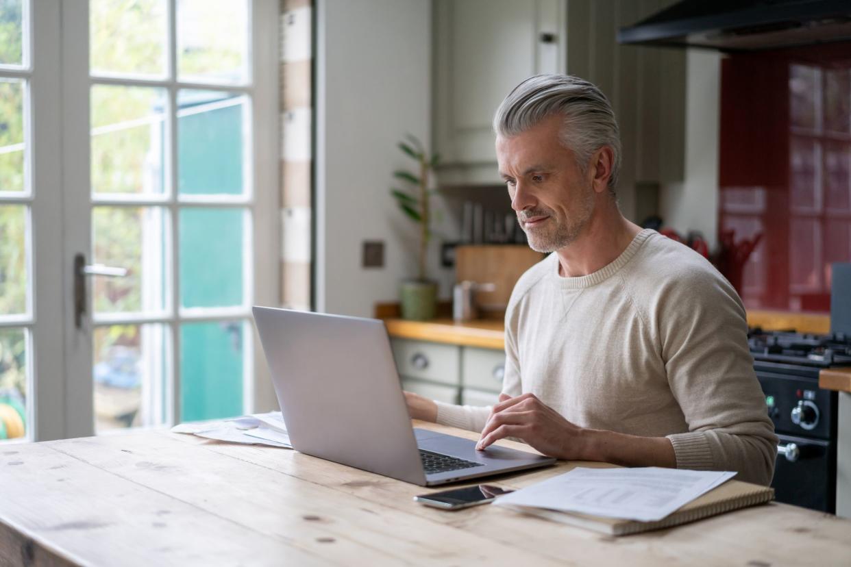 Portrait of an adult man working online at home on his laptop computer â€“ lifestyle concepts