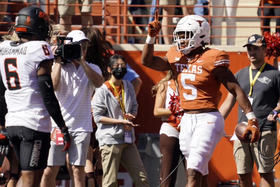 Texas running back Bijan Robinson (5) celebrates his touchdown past Oklahoma State cornerback Jabbar Muhammad (6) during the first half of an NCAA college football game in Austin, Texas, Saturday, Oct. 16, 2021. (AP Photo/Chuck Burton)