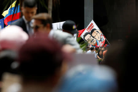 A supporter holds an image of Venezuela's re-elected President Nicolas Maduro next to the late Venezuelan President Hugo Chavez outside the National Electoral Council (CNE) in Caracas, Venezuela May 22, 2018. REUTERS/Carlos Garcia Rawlins