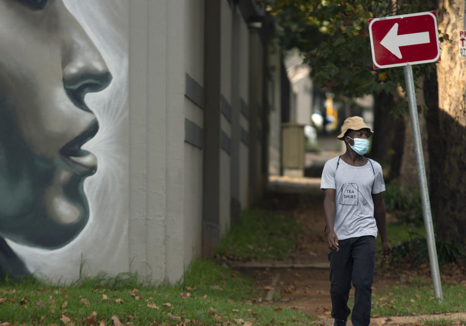 A pedestrian wearing a mask to protect against COVID-19 passes a wall mural on a sidewalk in Johannesburg, Wednesday, Feb. 24, 2021. In Finance Minister's budget speech in Parliament, Tito Mboweni said South Africa plans to spend dollars 712 million to vaccinate some 67% of its 60 million people to control the country's COVID-19 battle and get the economy to rebound from its decline of 7.2% last year. (AP Photo/Denis Farrell)