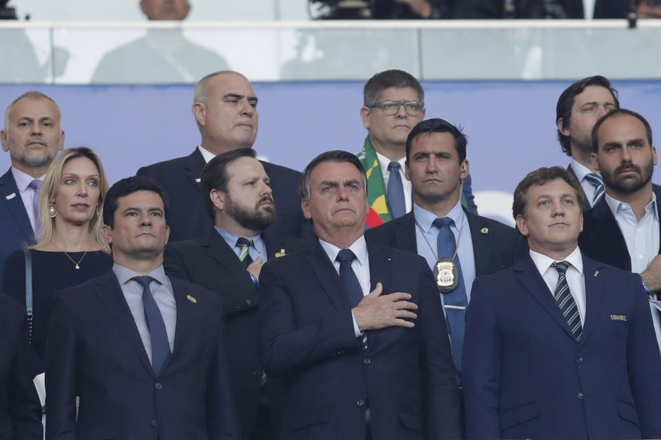 President Jair Bolsonaro, center, sings the national anthem next Brazil's Justice Minister Sergio Moro, left, and Conmebol President Alejandro Dominguez, right, prior to the final soccer match of the Copa America between Brazil and Peru at the Maracana stadium in Rio de Janeiro, Brazil, Sunday, July 7, 2019. (AP Photo/Andre Penner)