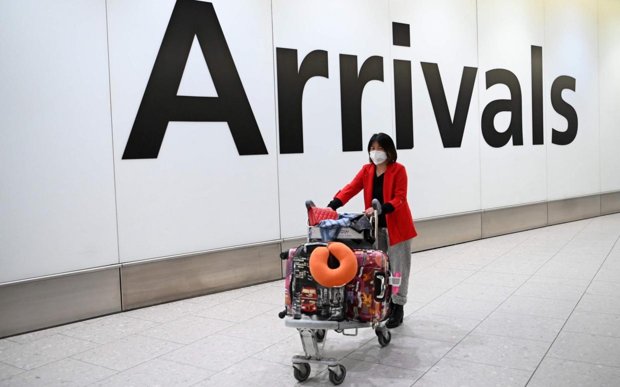 Passengers wear face masks as they arrive at London Heathrow Airport  - AFP