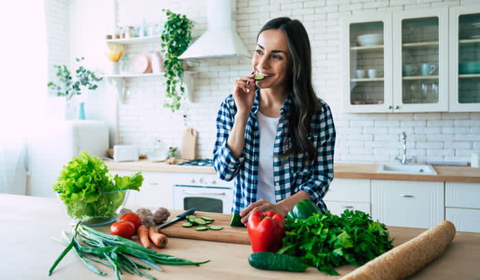 mujer comiendo verduras en casa