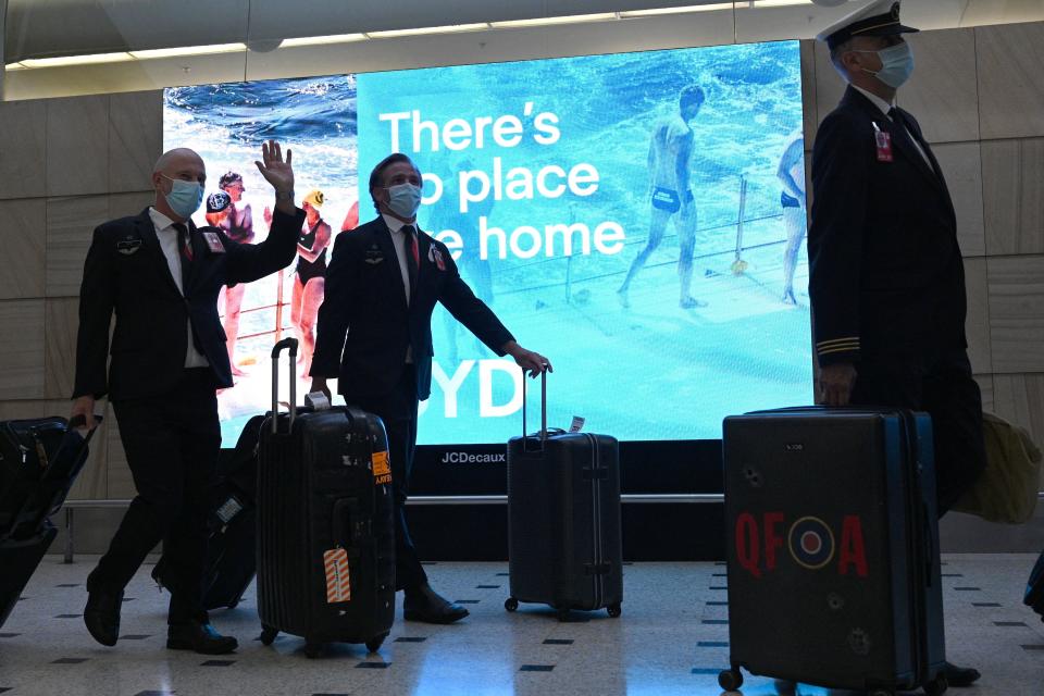 Flight crew wave as they come out from the arrival gates on the Sydney International airport on November 1, 2021, after Australia relaxed mandatory quarantine restrictions. (Photo by Saeed Khan / AFP) (Photo by SAEED KHAN/AFP via Getty Images)