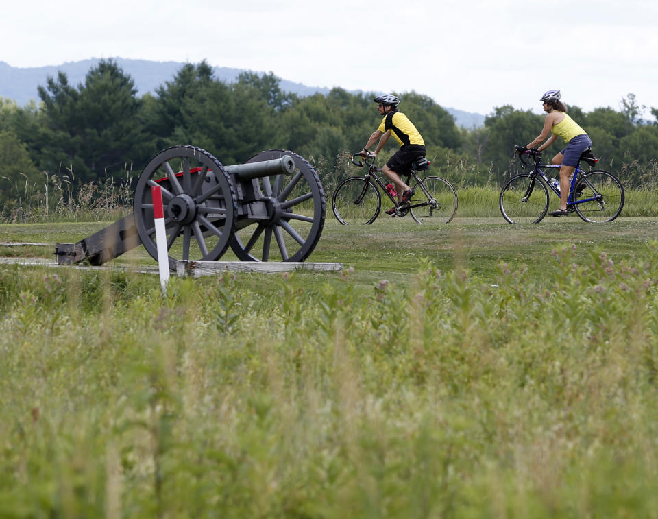 Eric Epstien, left, and Isabelle Davidowitz, of Braddock Heights, Maryland, ride past a cannon on a bike tour of Saratoga National Historical Park in Stillwater, N.Y., on Monday, July 2, 2012. The bike tours offer an opportunity to learn about a battle considered one of the most significant in history, while getting a not-too-strenuous workout at the same time. (AP Photo/Mike Groll)