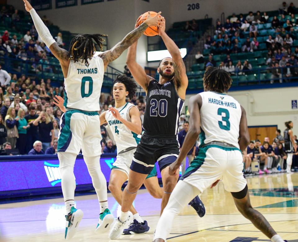 Monmouth's Tahron Allen drives against UNC Wilmington's Jamarii Thomas (0) and Maleeck Harde-Hayes (3) on Jan. 26, 2023 in Wilmington, North Carolina.