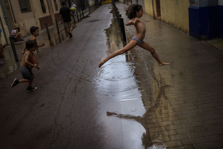 Los niños saltan sobre un charco de agua mientras juegan durante una tormenta en una calle de Barcelona, ​​España, el 18 de septiembre 
