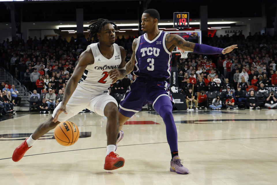 Cincinnati's Jizzle James, left, drives to the basket against TCU's Avery Anderson and during the first half of an NCAA college basketball game Tuesday, Jan. 16, 2024, in Cincinnati. (AP Photo/Jay LaPrete)