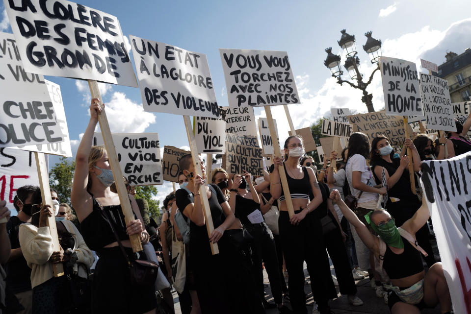 A woman holds a board reading '"Government Drink My Blood" as Women's rights activists protest against French President Emmanuel Macron's appointment of an interior minister who has been accused of rape and a justice minister who has criticized the #MeToo movement, in front of Paris city hall, in Paris, France, Friday, July 10, 2020. The French government said it remains committed to gender equality and defended the new ministers, stressing the presumption of innocence. Gerald Darmanin, Interior Minister, firmly denies the rape accusation, and an investigation is underway. New Justice Minister Eric Dupond-Moretti is a lawyer who has defended a government member accused of rape and sexual assault, and has ridiculed women speaking out thanks to the #MeToo movement. (AP Photo/Francois Mori)