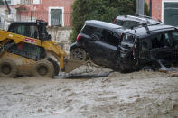 A caterpillar removes damaged cars in a flooded street after heavy rainfall triggered landslides that collapsed buildings and left as many as 12 people missing, in Casamicciola, on the southern Italian island of Ischia, Saturday, Nov. 26, 2022. Firefighters are working on rescue efforts as reinforcements are being sent from nearby Naples, but are encountering difficulties in reaching the island either by motorboat or helicopter due to the weather. (AP Photo/Salvatore Laporta)