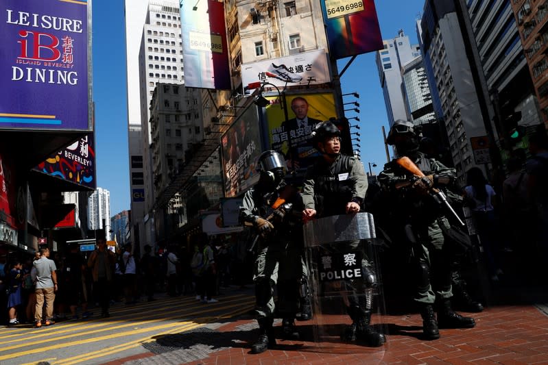 Riot policemen watch at a junction in Causeway Bay district before a protest march in Hong Kong