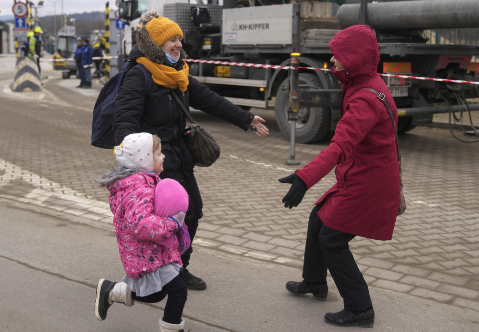 A woman, right, puts out her arms to welcome her sister and niece, who fled Ukraine, at the border crossing in Kroscienko, Poland, Tuesday, March 8, 2022. Russia's invasion of Ukraine has set off the largest mass migration in Europe in decades, with more than 1.5 million people having crossed from Ukraine into neighboring countries. (AP Photo/Markus Schreiber)