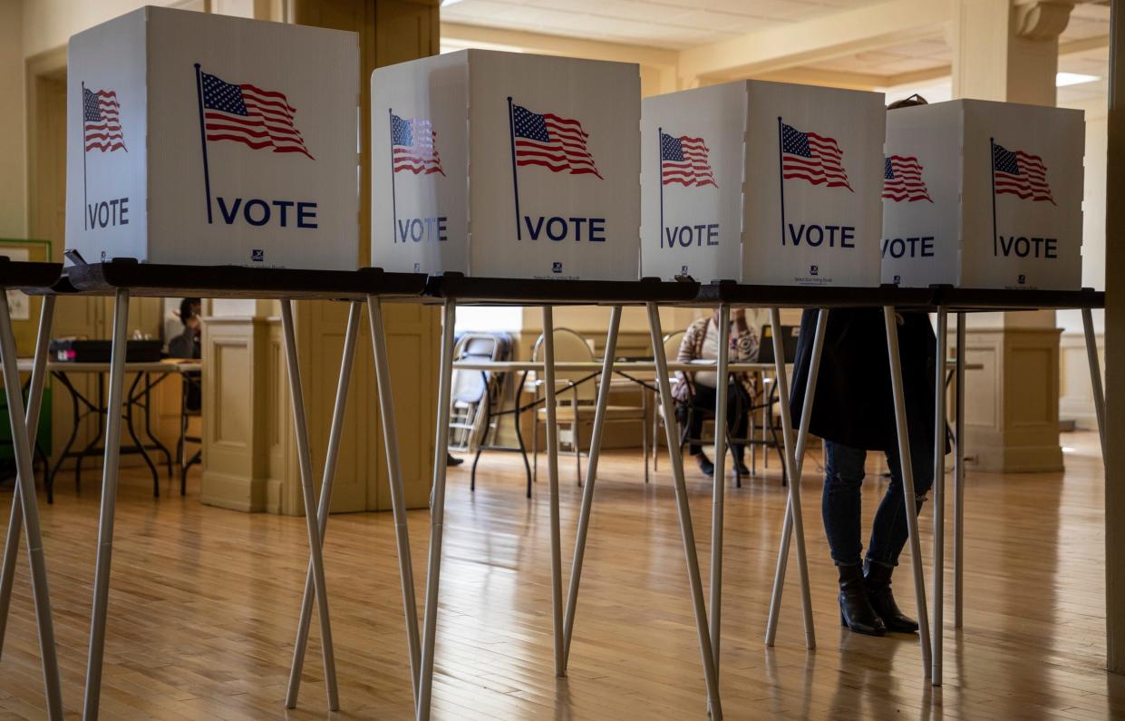 A person stands behind a voting booth as they cast their vote inside the Central United Methodist Church polling place in Detroit on Nov. 8, 2022.